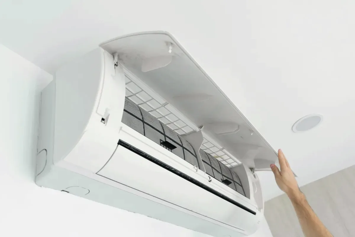 Hand opening the cover of a wall-mounted ductless air conditioner